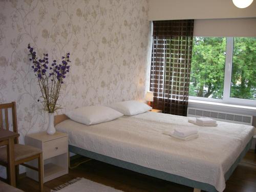 een slaapkamer met een bed met een vaas met bloemen erop bij Sõrve Guest House in Salme