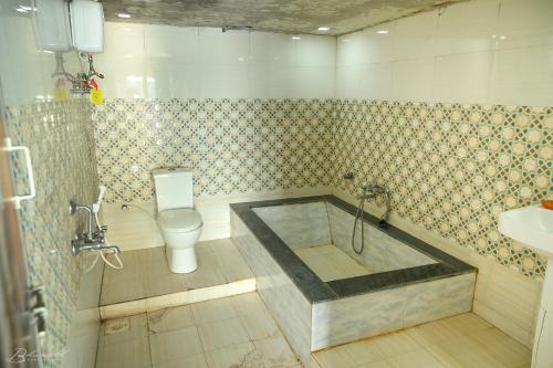 a bathroom with a tub with a toilet and a sink at Sattva camps and cottages - Udupi in Udupi