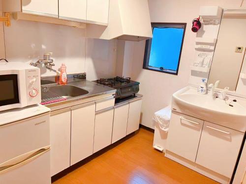a white kitchen with a sink and a microwave at Youki Residence in Tokyo
