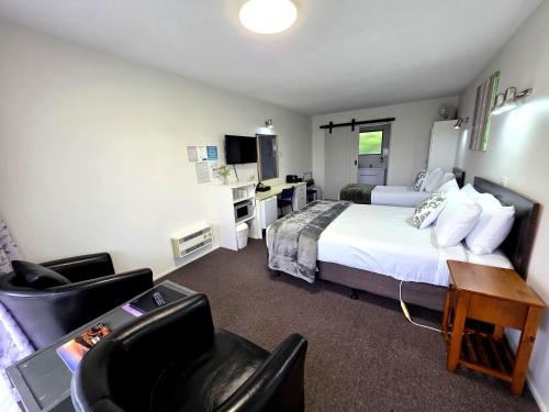 a hotel room with a bed and a desk and chairs at Arran Motel in Te Anau