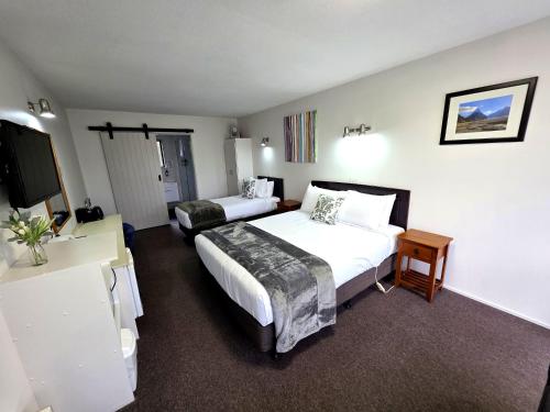 a hotel room with two beds and a flat screen tv at Arran Motel in Te Anau