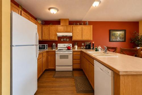 a kitchen with a white refrigerator and wooden cabinets at Suite Serenity Condo by NW Comfy Cabins in Leavenworth