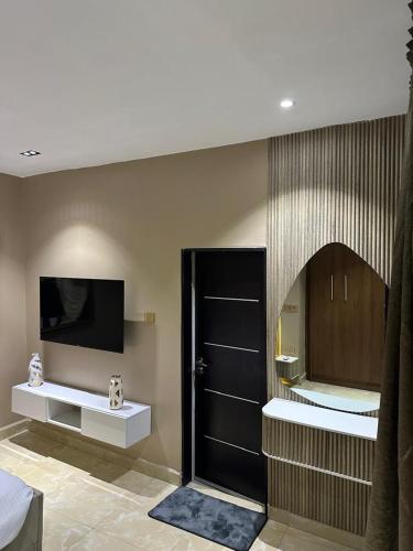 a room with a tv and a door with a mirror at Grey Ivy Apartment in Abuja