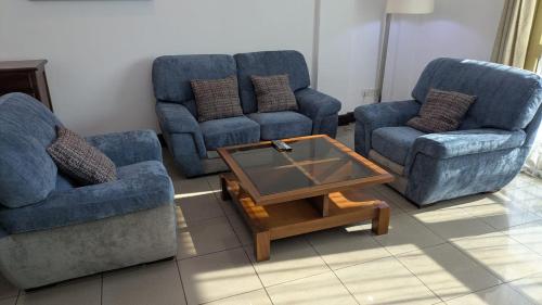 a living room with three blue chairs and a coffee table at Résidence shalismi in Yaoundé