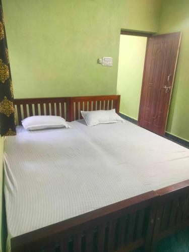 a bedroom with a large bed with white sheets at Manjunatha nilaya sute delux ordinary room in Kollūru
