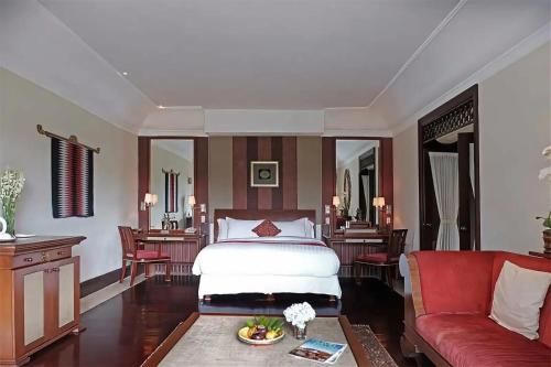a bedroom with a bed and a red couch at Anhera Suite Ubud in Ubud