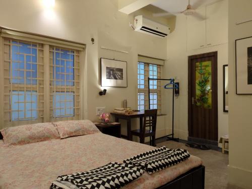 a bedroom with a bed and a desk and windows at Disharee 51A in Kolkata