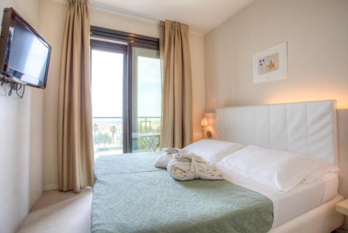 a bedroom with a bed with a television and a window at Ferretti Beach Hotel in Rimini