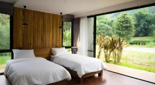 two beds in a bedroom with a large window at Villa De View in Ban Tham