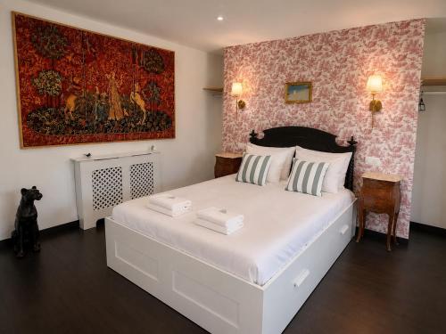 a bedroom with a large white bed and a painting on the wall at Domaine de la Jasseix in Croze