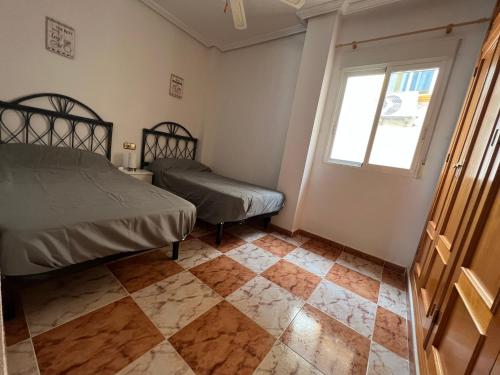 a bedroom with a bed and a window and a tiled floor at Lima in Orihuela Costa