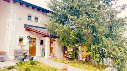 a white house with a tree in front of it at Alpine Home with Lounge - 10 min from St Moritz in La Punt-Chamues-ch
