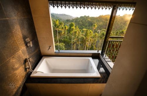 a bath tub in front of a window with a view at Ynad Mount Resort in Meppādi