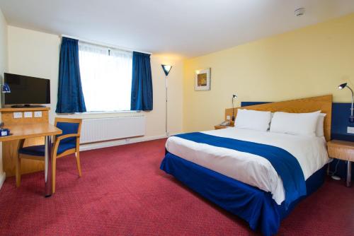 a hotel room with a bed and a desk and a television at Holiday Inn Express Bradford City Centre by IHG in Bradford