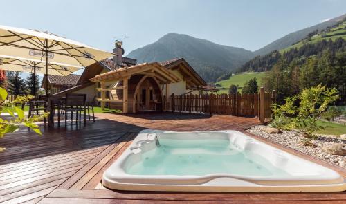 a hot tub on a deck in front of a house at Hotel Appartement Haus Gitschberg in Vandoies