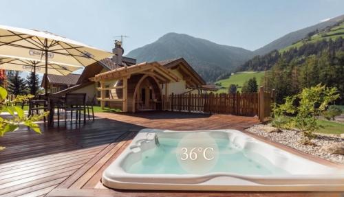 a hot tub on a deck in front of a house at Hotel Appartement Haus Gitschberg in Vandoies