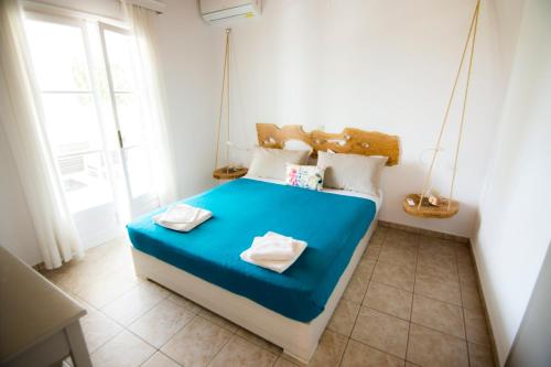 a bedroom with a blue bed with two towels on it at Serenity Apartments, Next to the Beach in Agios Georgios