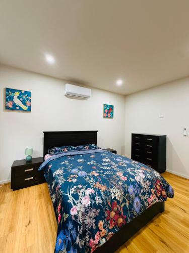 a bedroom with a bed with a floral bedspread at Grand Suite with Ensuite Bathroom in Wyndham Vale