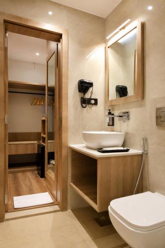 ein Badezimmer mit Toilette, Waschbecken und Spiegel in der Unterkunft Rahitya Pr,emier, Ayodhya in Faizābād