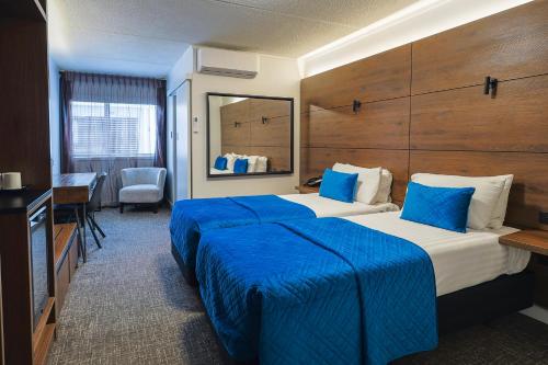 a hotel room with two beds with blue sheets at The Ashley Hotel Greymouth in Greymouth