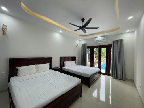 a bedroom with two beds and a ceiling fan at Mori Khem Beach Homestay in Phú Quốc