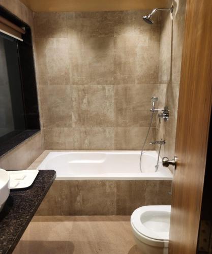 a bathroom with a tub and a toilet and a sink at Tangerine Boutique Resort in Calangute