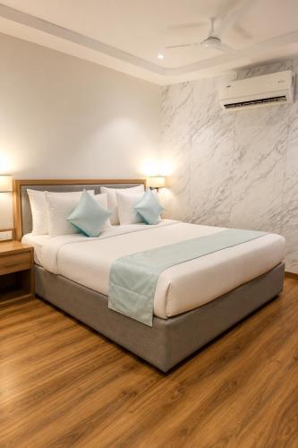 ein Schlafzimmer mit einem großen Bett mit weißen Laken und blauen Kissen. in der Unterkunft Rahitya Pr,emier, Ayodhya in Faizābād