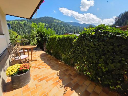 a patio with a table and chairs and a hedge at Feines Alpennest in Hopfgarten im Brixental