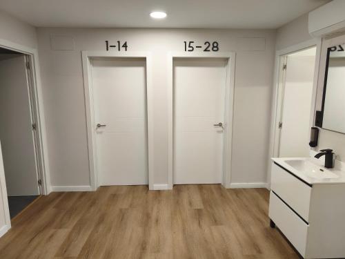 a bathroom with two white doors and a sink at Albergue O Centro in Portomarin