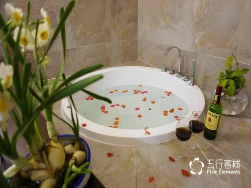 a bath tub with flowers and bottles of wine at Dali Five Elements Hostel in Dali Ancient Town