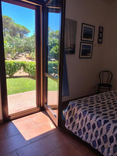 a bedroom with a bed and a sliding glass door at Rosanna House in Bombarde Beach in Alghero