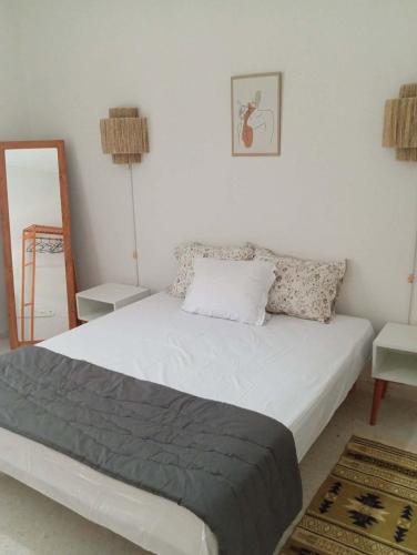 a bedroom with a white bed with a mirror at DAR Essaad in Wadhraf
