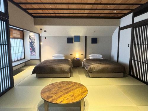 a room with two beds and a wooden table at Hotel Clio Court Hakata in Fukuoka