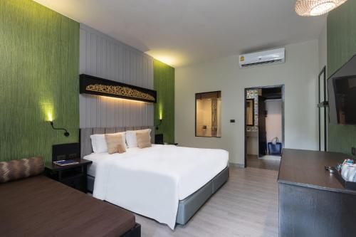 a bedroom with a large white bed and a couch at Deevana Patong Resort & Spa in Patong Beach