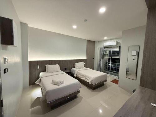 a hotel room with two beds and a mirror at Nonsi Hotel Phitsanulok in Ban Wat Tha Maprang