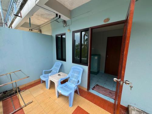 two blue chairs and a table on a porch at Tommy Apartment - main road in Ko Tao