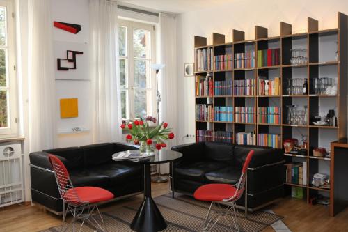 a living room with a couch and chairs and a book shelf at Hotel am Main in Veitshöchheim