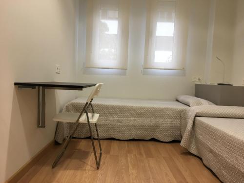 a room with two beds and a desk and a chair at Pensión-Albergue Puente Ribeira in Sarria