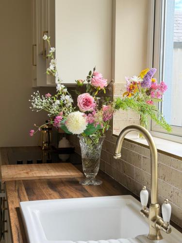 a vase filled with flowers sitting next to a sink at Glebe cottage in Kinvara