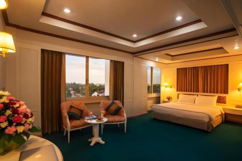 a hotel room with a bed and a chair at Wangtai Hotel in Suratthani