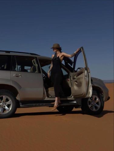 a woman is getting out of a vehicle at Camel Trekking Camp & Activities in Merzouga