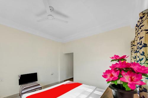 a room with a bed and a tv and pink flowers at Hotel O Dream Marion in Bhubaneshwar