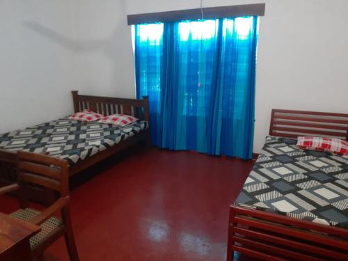 two beds in a room with blue curtains at Gal Bungalow in Elpitiya