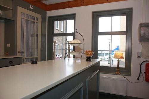 eine Küche mit einer weißen Theke und 2 Fenstern in der Unterkunft Bed & Breakfast De Roos in Urk