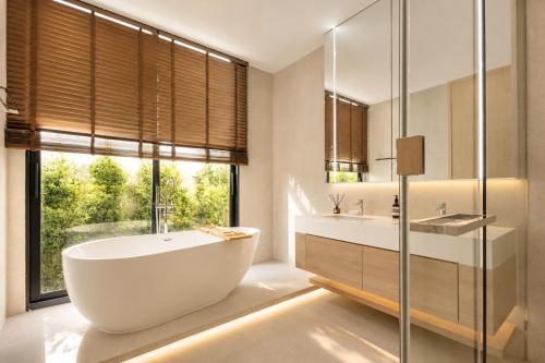 a bathroom with a tub and a sink and a window at Le Da Villas 5BR Bang Tao Beach in Laguna Phuket