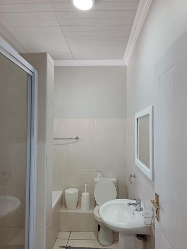 a white bathroom with a sink and a toilet at Unit 18 Kei Sands Resort in Kei-mouth Village