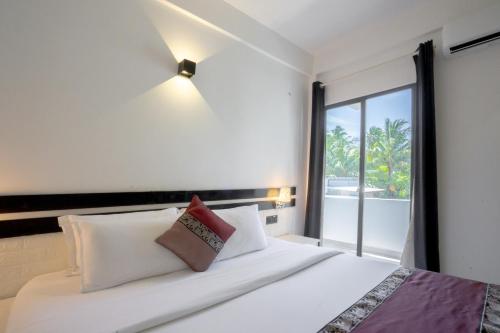 a bedroom with a bed with a large window at Cozy Roots Fuvahmulah in Fuvahmulah