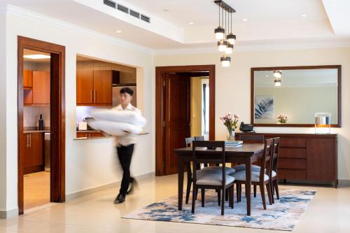 a man is carrying a bed in a kitchen at Sedra Arjaan by Rotana in Doha