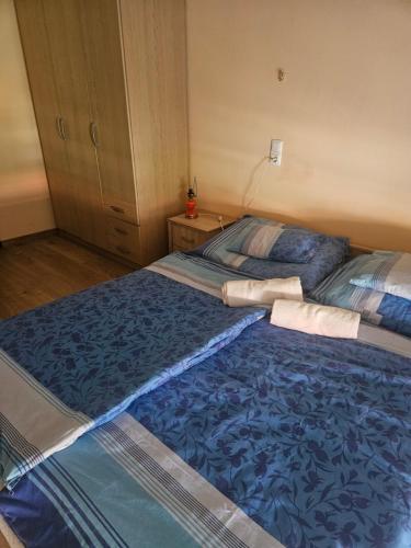 a bedroom with two beds with blue sheets at Cserke-Thermál Apartman in Cserkeszőlő