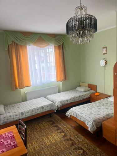 a room with three beds and a chandelier at Coffee Hostel in Lviv